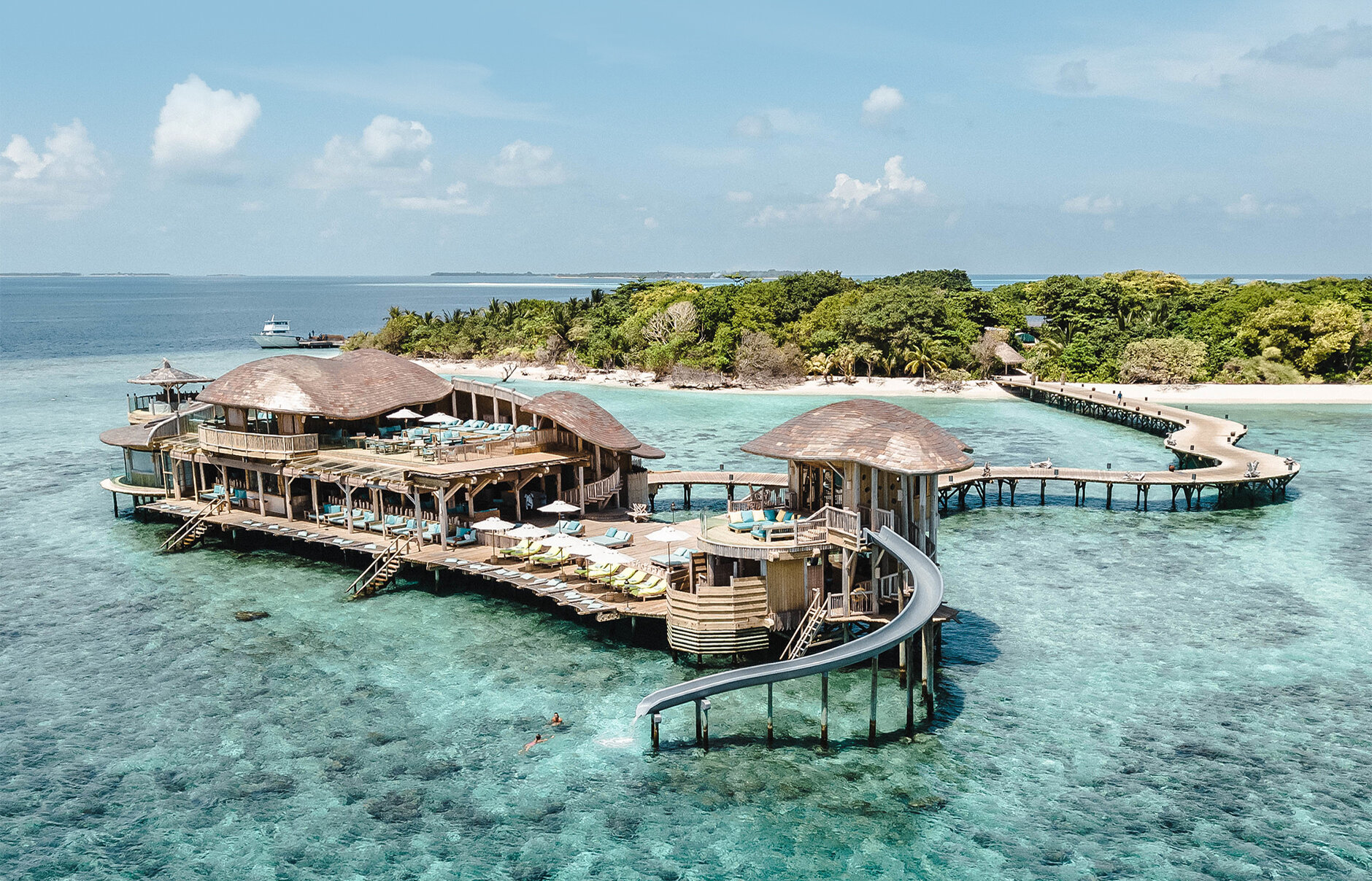 Holiday resort set in the middle of the turquoise coloured sea, palm trees and bright green shrubbery in the background