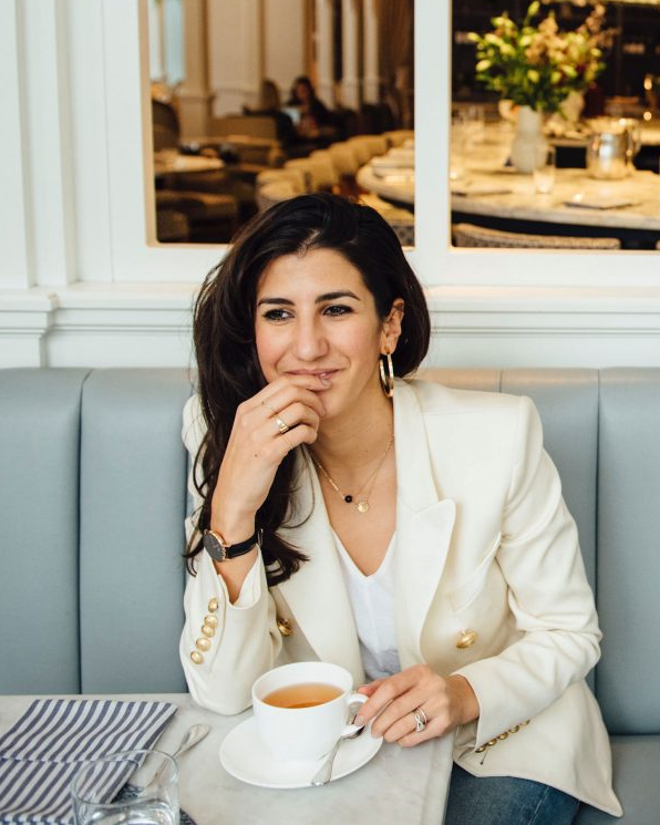 Woman in a white jacket, sitting in a restaurant drinking tea 