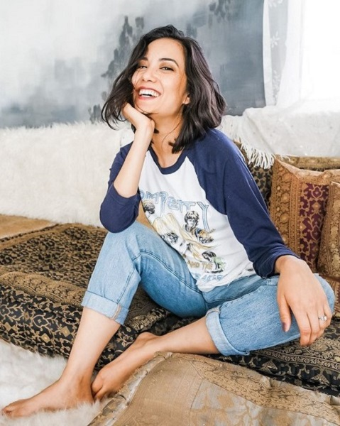 Woman smiling, sitting on a brown patterned rug