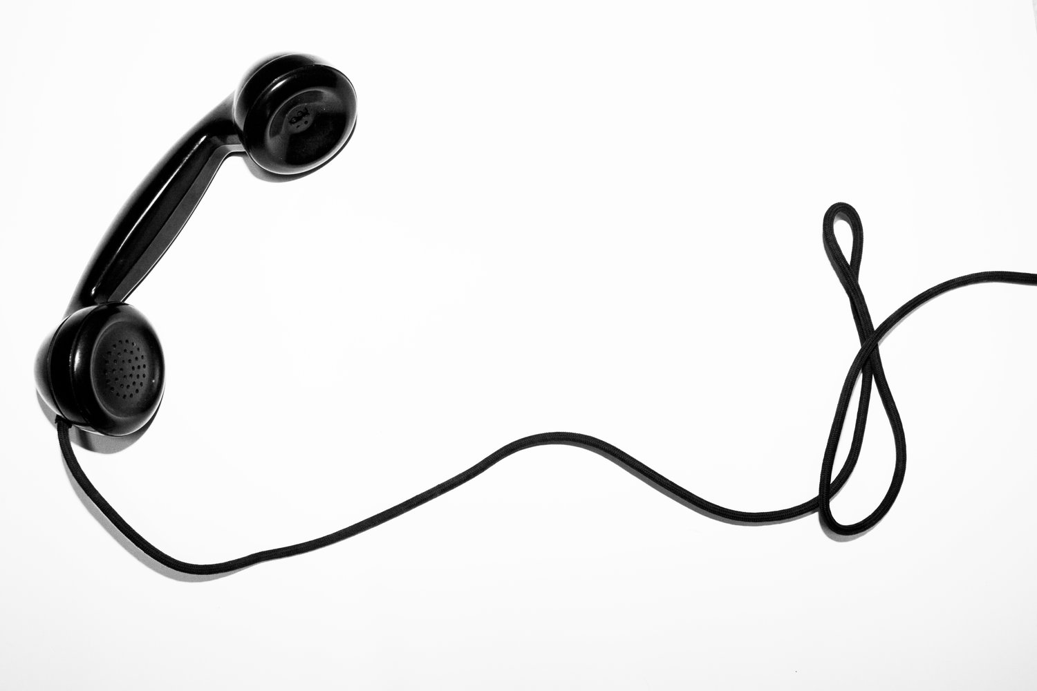 Black and white image of a telephone with a long black curving wire attached.